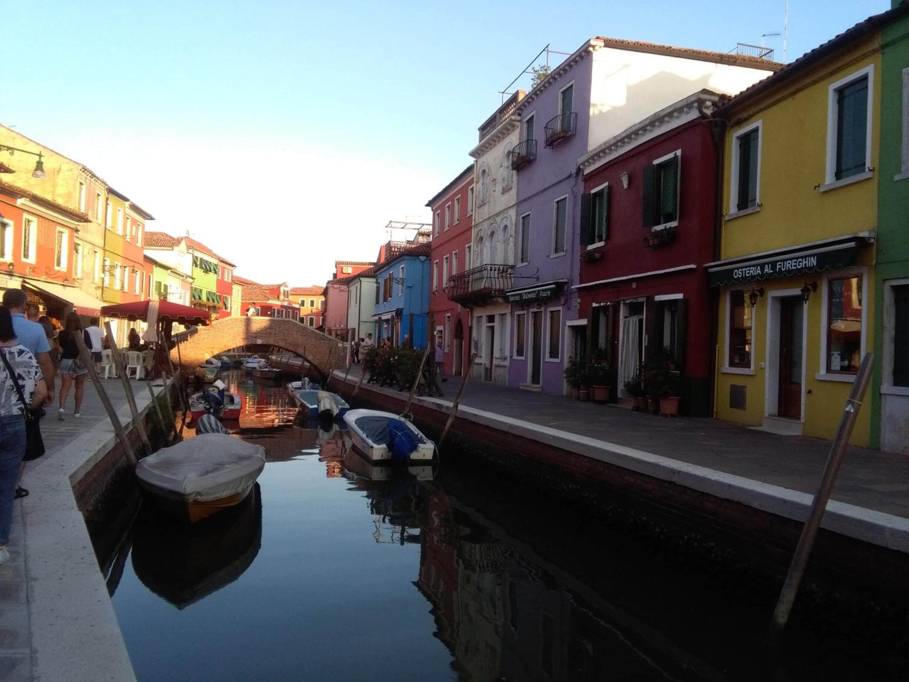 Un canal con barcos, edificios coloridos y un puente.