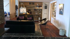 Un salon moderne avec un canapé noir, un tapis à motifs et une bibliothèque.