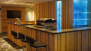Un espace bar avec des lambris en bois, une machine à café et des tabourets de bar.