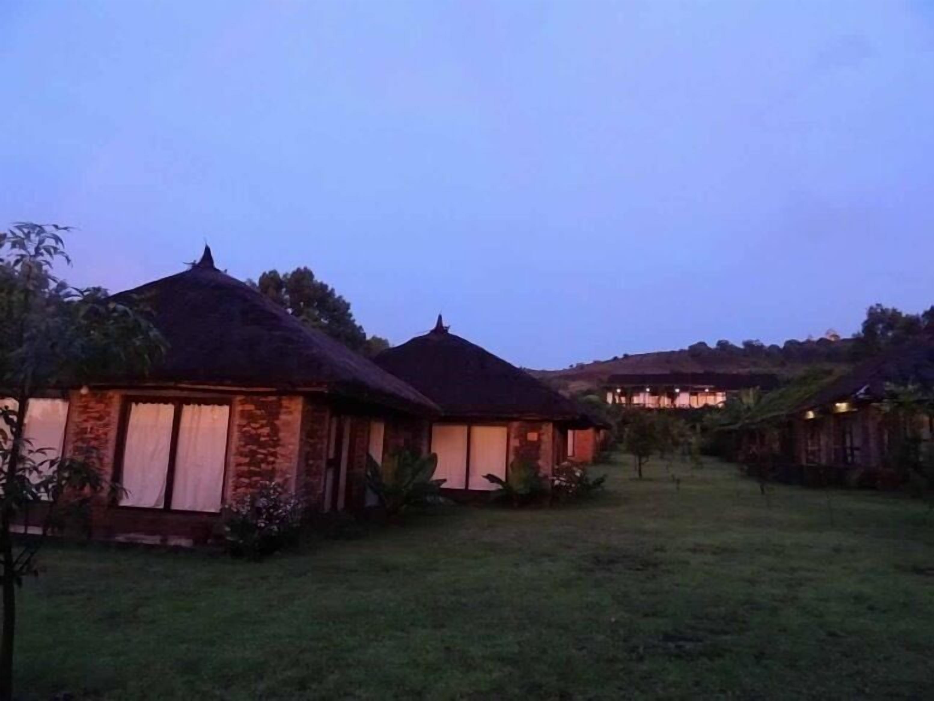 A rural setting with thatched-roof cottages and a grassy area.