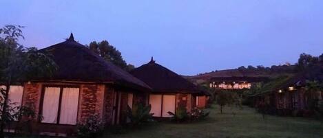 A rural setting with thatched-roof cottages and a grassy area.