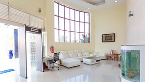 A spacious living area with a white sofa, a glass coffee table, and a large window.