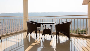 A balcony with a table and two chairs, offering a view of a distant landscape.