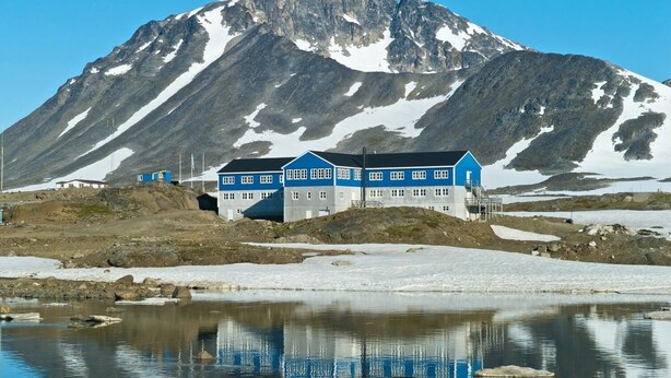 Un bâtiment bleu avec une montagne en arrière-plan.