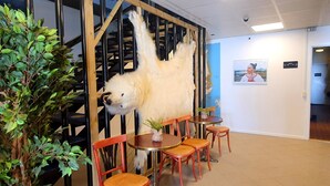 Une pièce comprenant une grande sculpture d’un ours polaire, des chaises en bois, une petite table et une carte accrochée au mur.