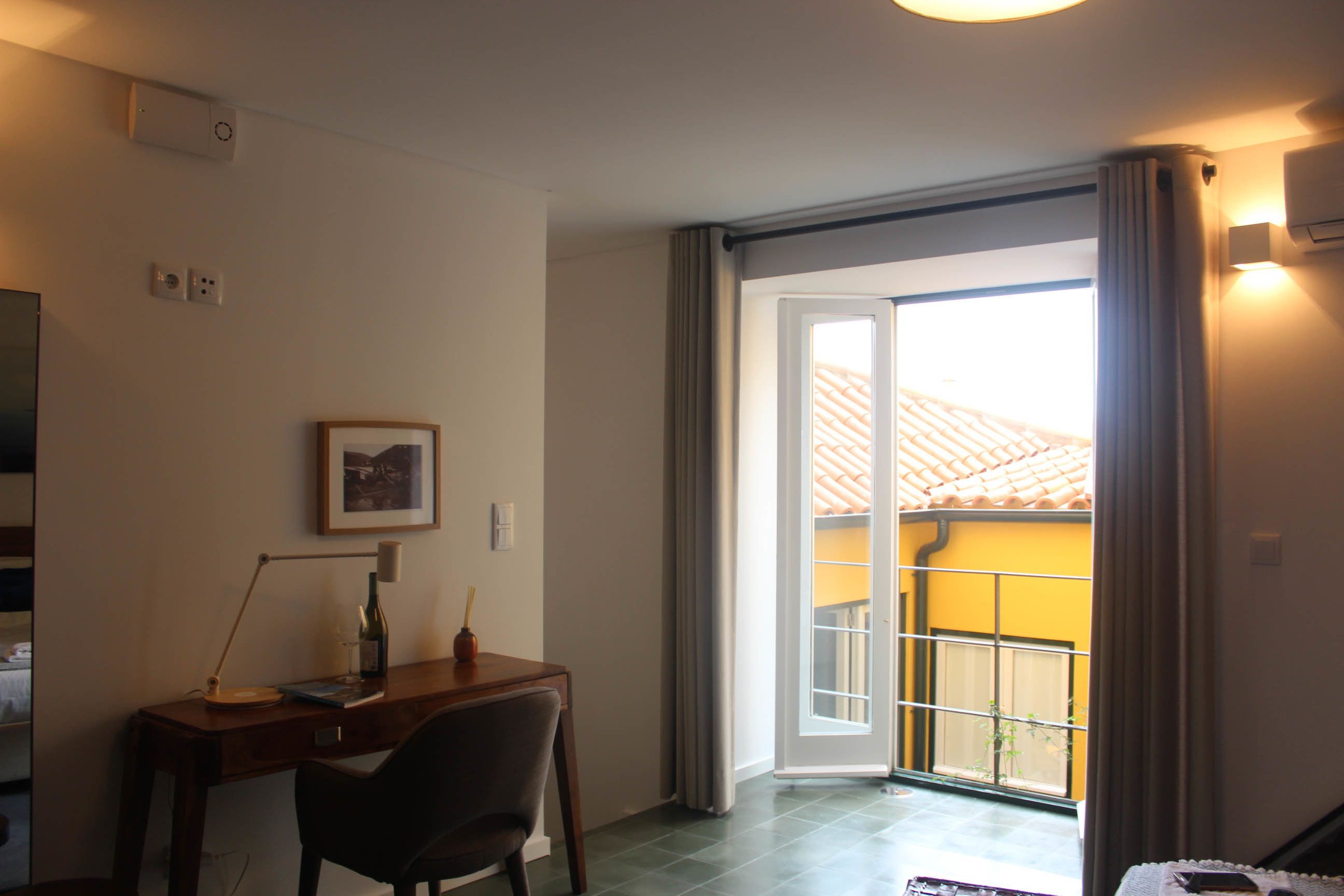 A room with a desk, chair, and a window with curtains.