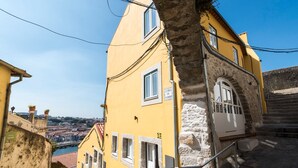 A yellow building with a stone staircase and a view of the city. - Arco Apartments (Porto)