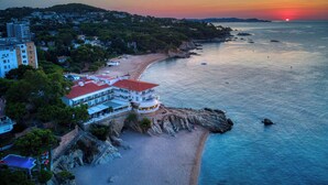 Un hotel frente al mar con vista a la playa, piscina y costa rocosa.