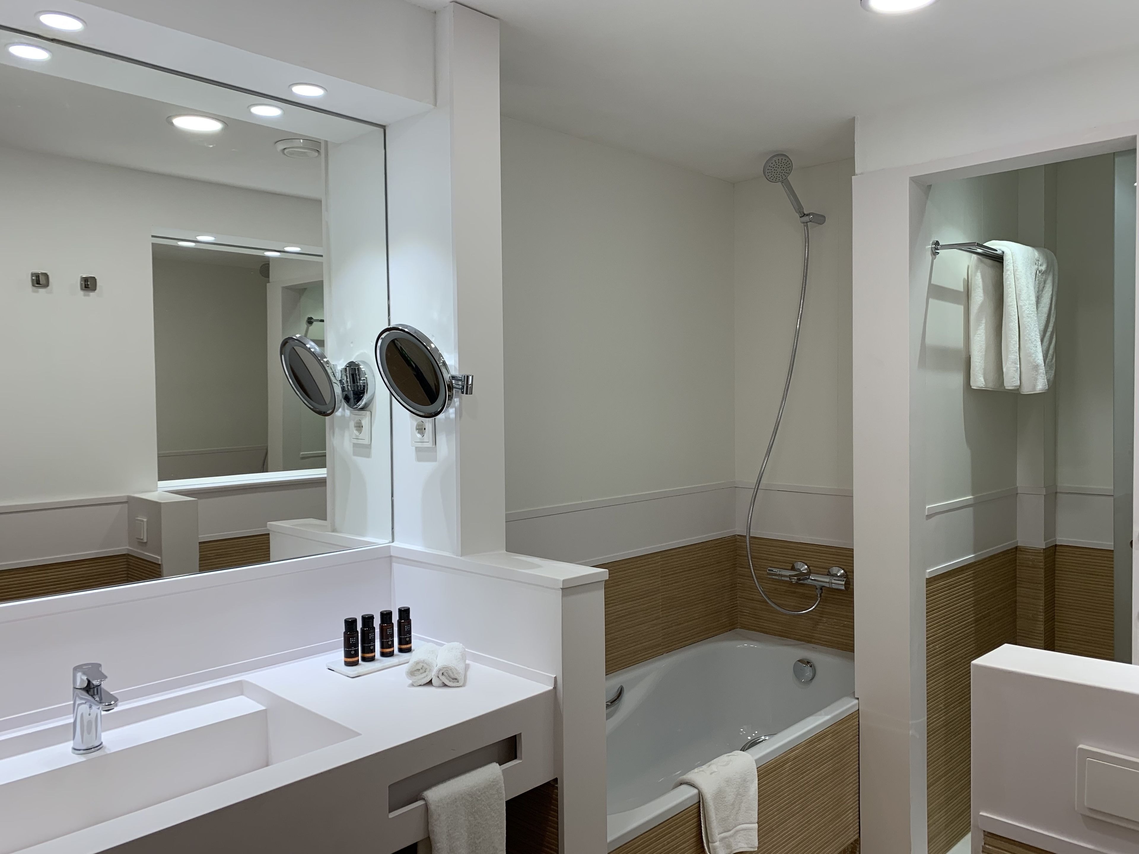 A modern bathroom with a large mirror, a bathtub, and a shower.