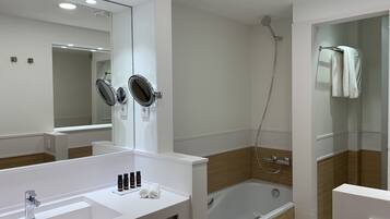 A modern bathroom with a large mirror, a bathtub, and a shower.