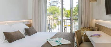 A hotel room with a bed, a desk, and a view of the outside.