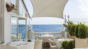 Una terraza con mesas listas para comer, con vista al mar.