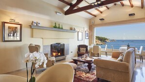 Amplia sala de estar con chimenea, asientos cómodos y vista al mar.