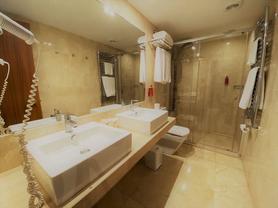 A modern bathroom with two sinks, a shower, and a toilet.