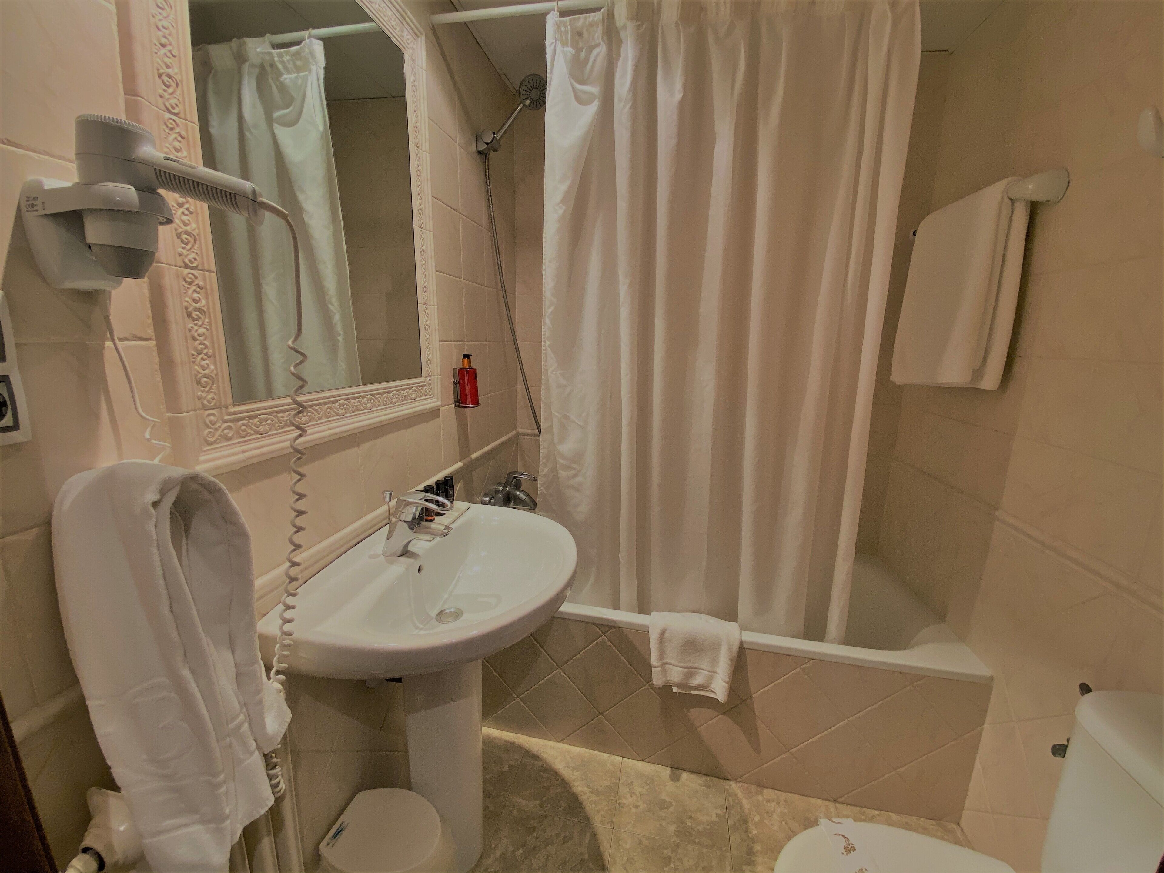 A bathroom with a sink, toilet, shower, and a towel rack.