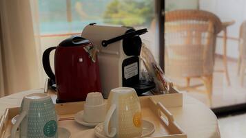 Una mesa con una cafetera, un hervidor y una bandeja con tazas y platillos.