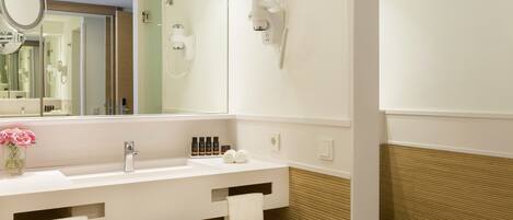 A modern bathroom with a white sink, a mirror, a hairdryer, and a toilet.
