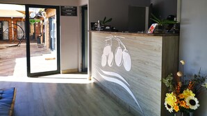 A reception area with a wooden counter, a signboard, and a potted plant. - The Green Olive Guesthouse (Bethlehem)