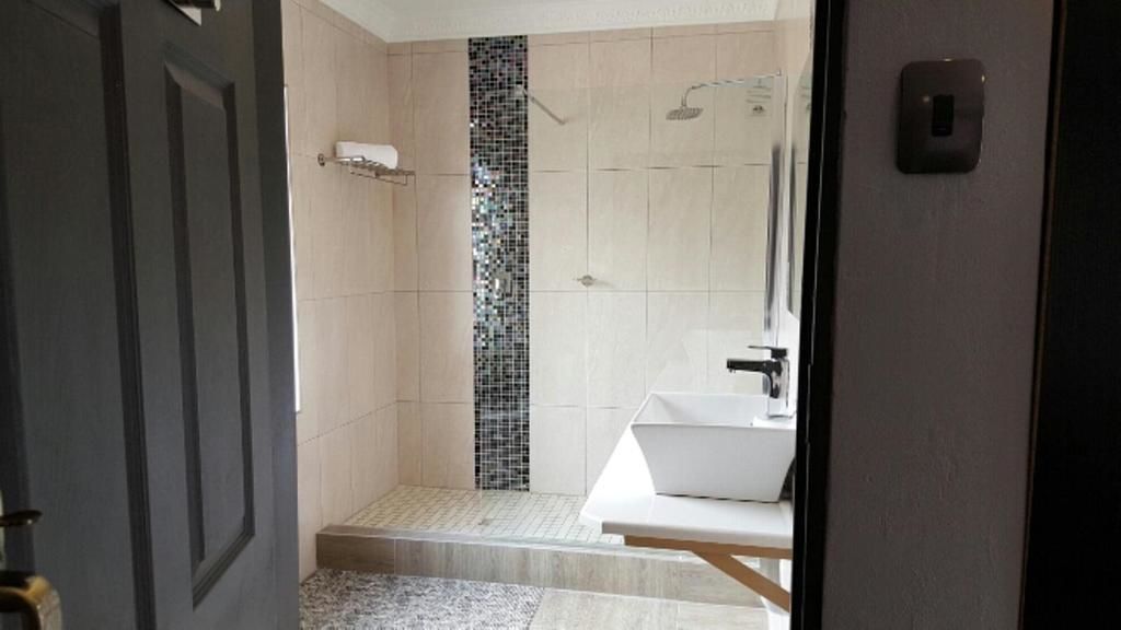 A modern bathroom with a shower, a sink, and a mirror.