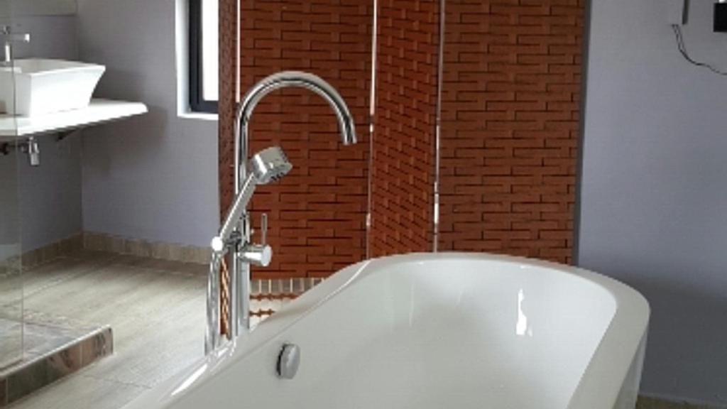 A modern bathroom with a freestanding bathtub, a wall-mounted sink, and a visible window.