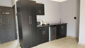 A compact kitchen with dark cabinets, a microwave, and a dishwasher. - The Green Olive Guesthouse (Bethlehem)