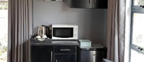 A compact kitchenette with a microwave, coffee maker, and a small refrigerator.