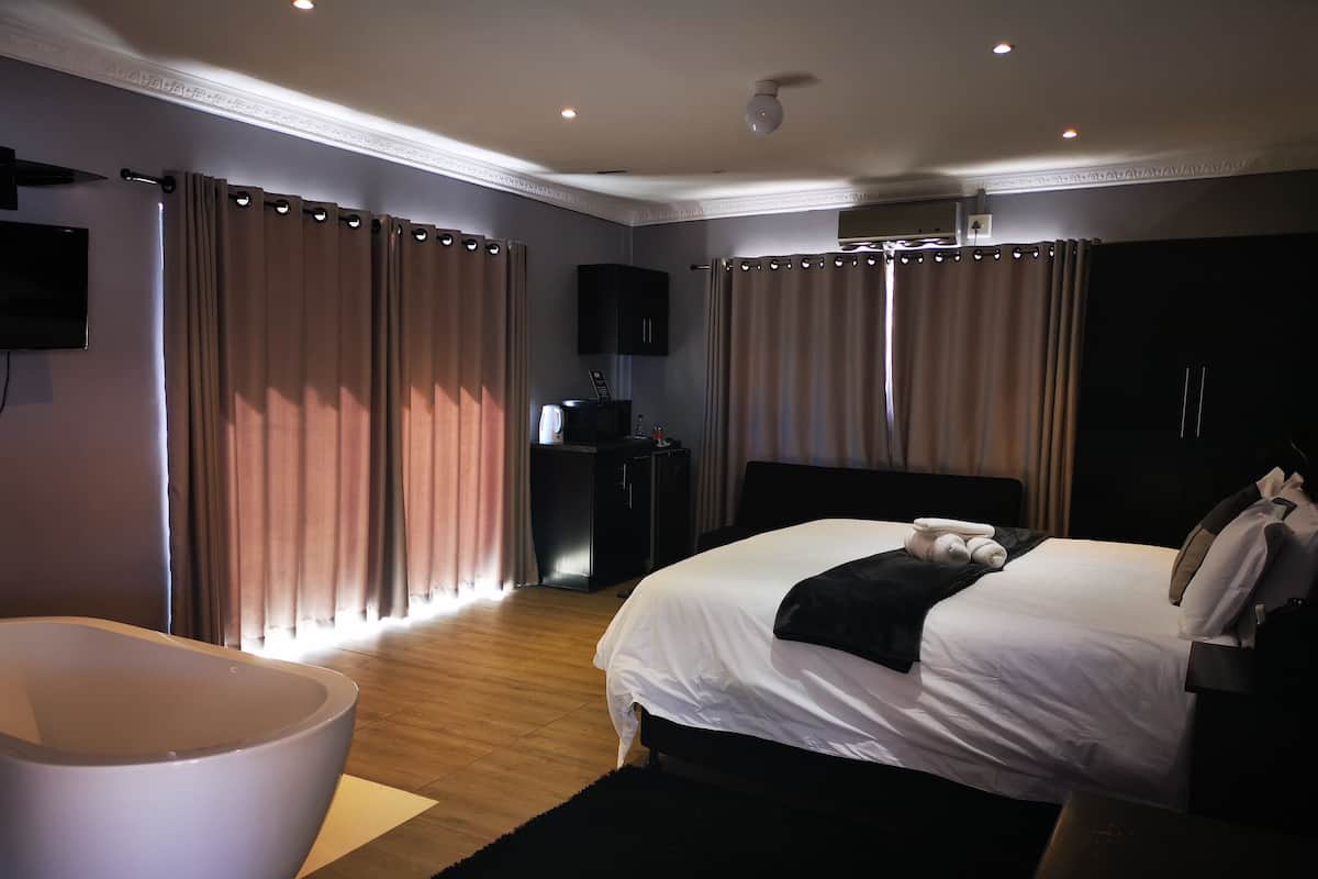 A modern hotel room with a large bed, a flat-screen TV, a desk, and a wardrobe.