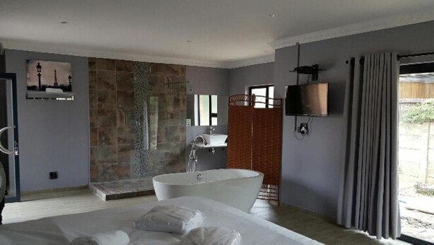 A modern bathroom with a freestanding bathtub, a glass shower enclosure, and a large mirror. - The Green Olive Guesthouse (Bethlehem)
