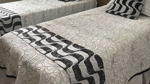 Habitación de hotel con dos camas individuales, cada una con ropa de cama y almohadas estampadas.