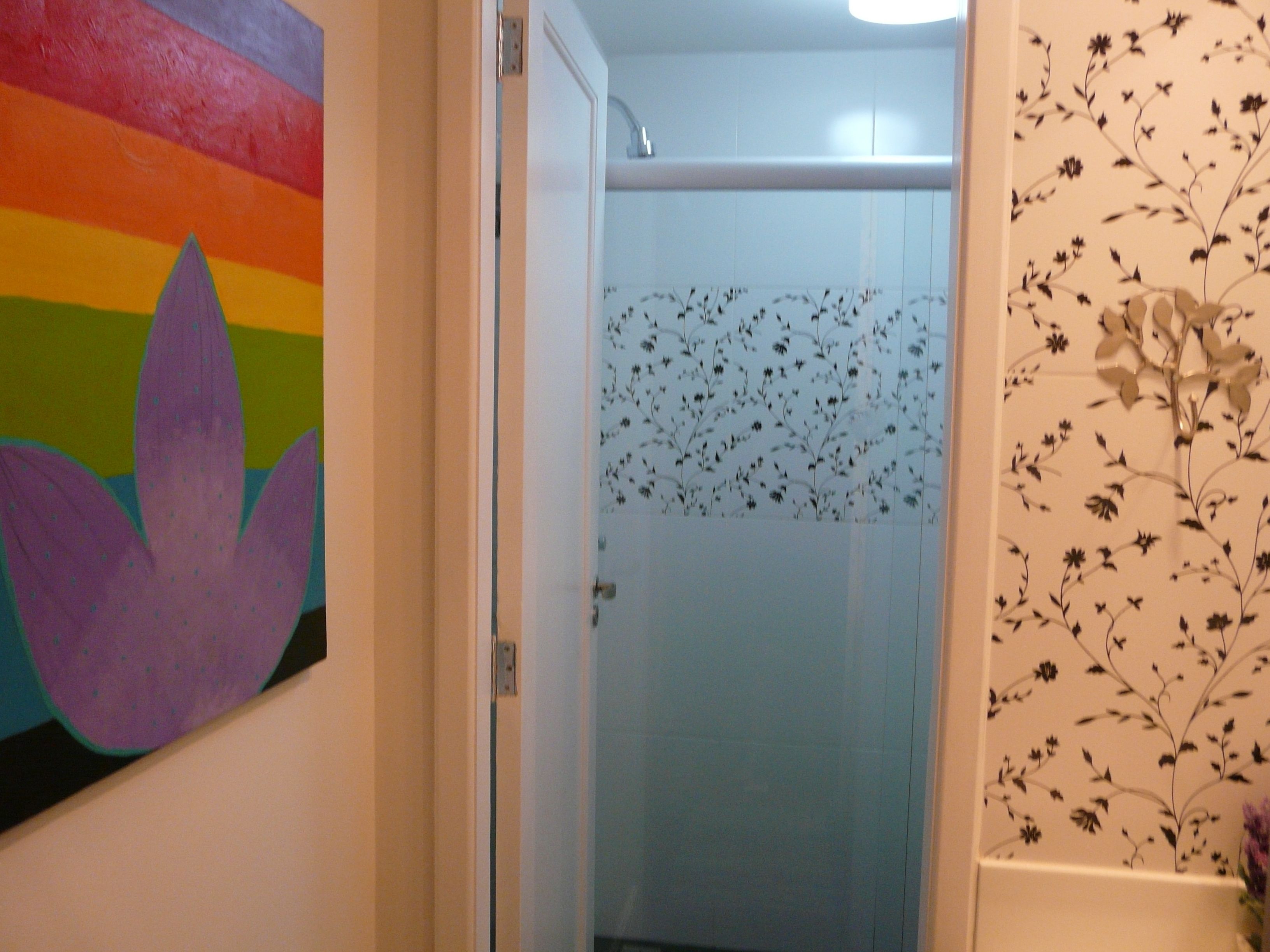 Ein Badezimmer mit Dusche, farbenfroher Wandgestaltung und floralem Wandpapier.
