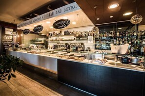 Un café doté d’un bar, d’étagères remplies de bouteilles et d’un comptoir buffet.