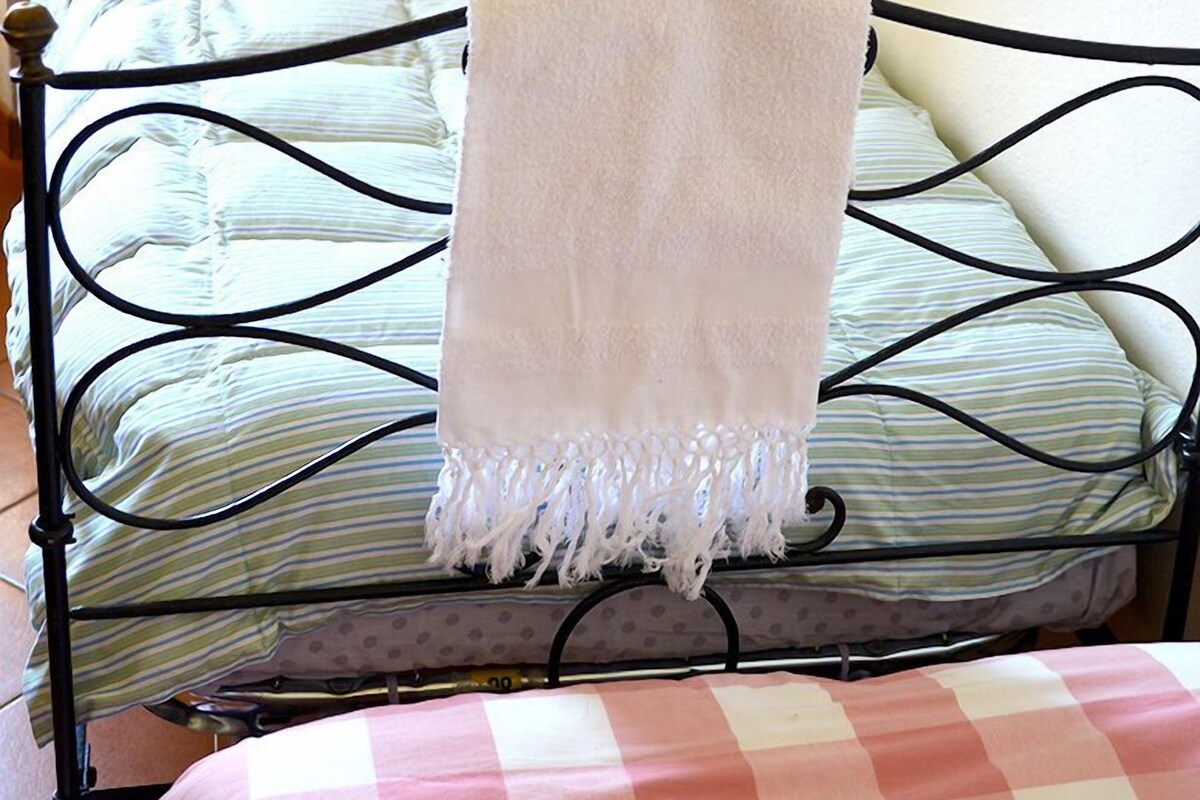 A metal-framed bed with a white blanket and a checkered bedspread.