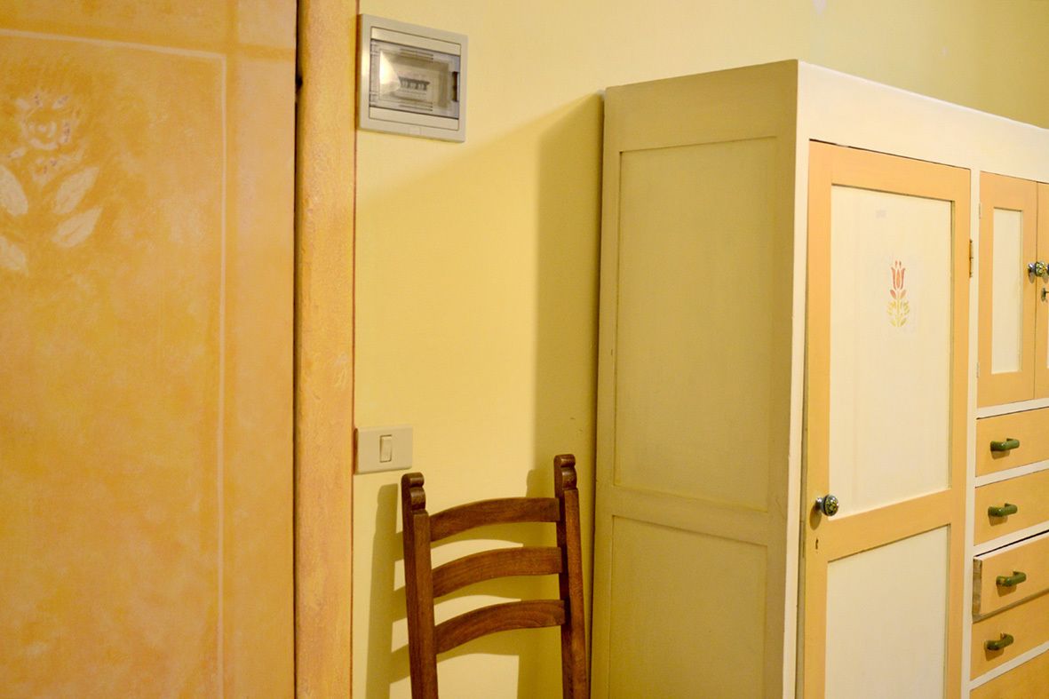 A room with a wooden chair, a closed door, and a cabinet with drawers.
