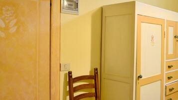 A room with a wooden chair, a closed door, and a cabinet with drawers.