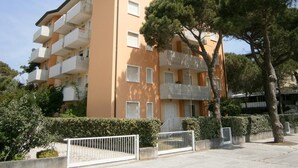 Un immeuble résidentiel à plusieurs étages, doté de balcons, d’une entrée sécurisée et entouré de verdure.