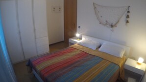 Une chambre à coucher comprenant un lit, des tables de chevet, une armoire et un élément décoratif mural.