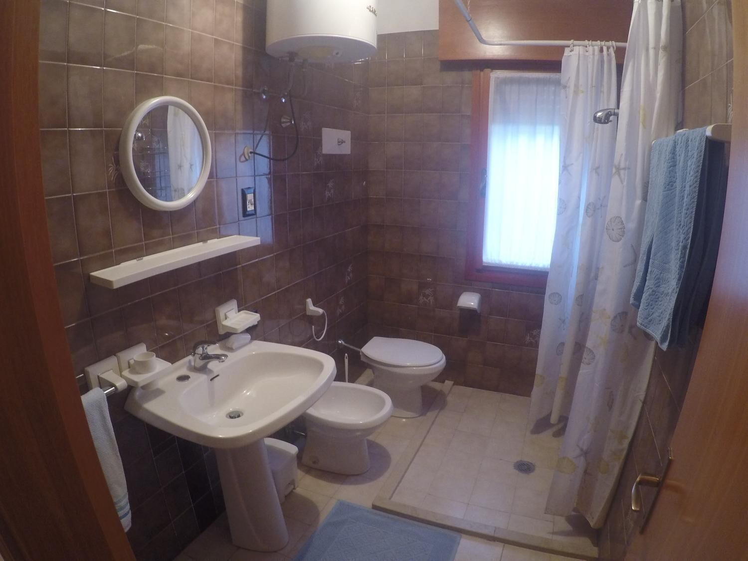 A bathroom with a sink, two toilets, a mirror, and a shower curtain.
