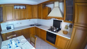 A compact kitchen with wooden cabinets, a microwave, a stove, and a sink.