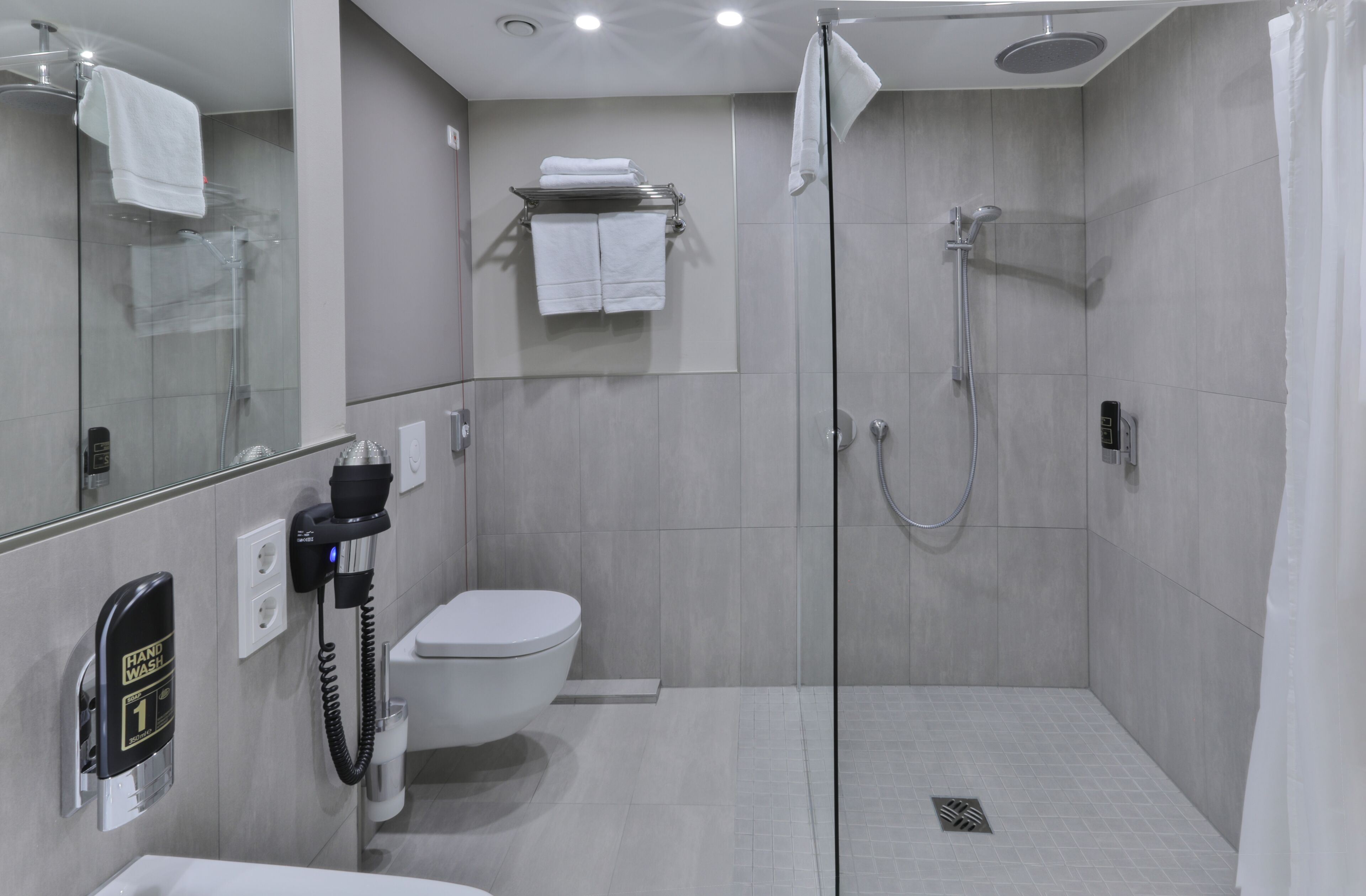 Een moderne badkamer met een douchecabine van glas, een toilet en een wastafel.