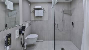 Een moderne badkamer met een douchecabine van glas, een toilet en een wastafel.