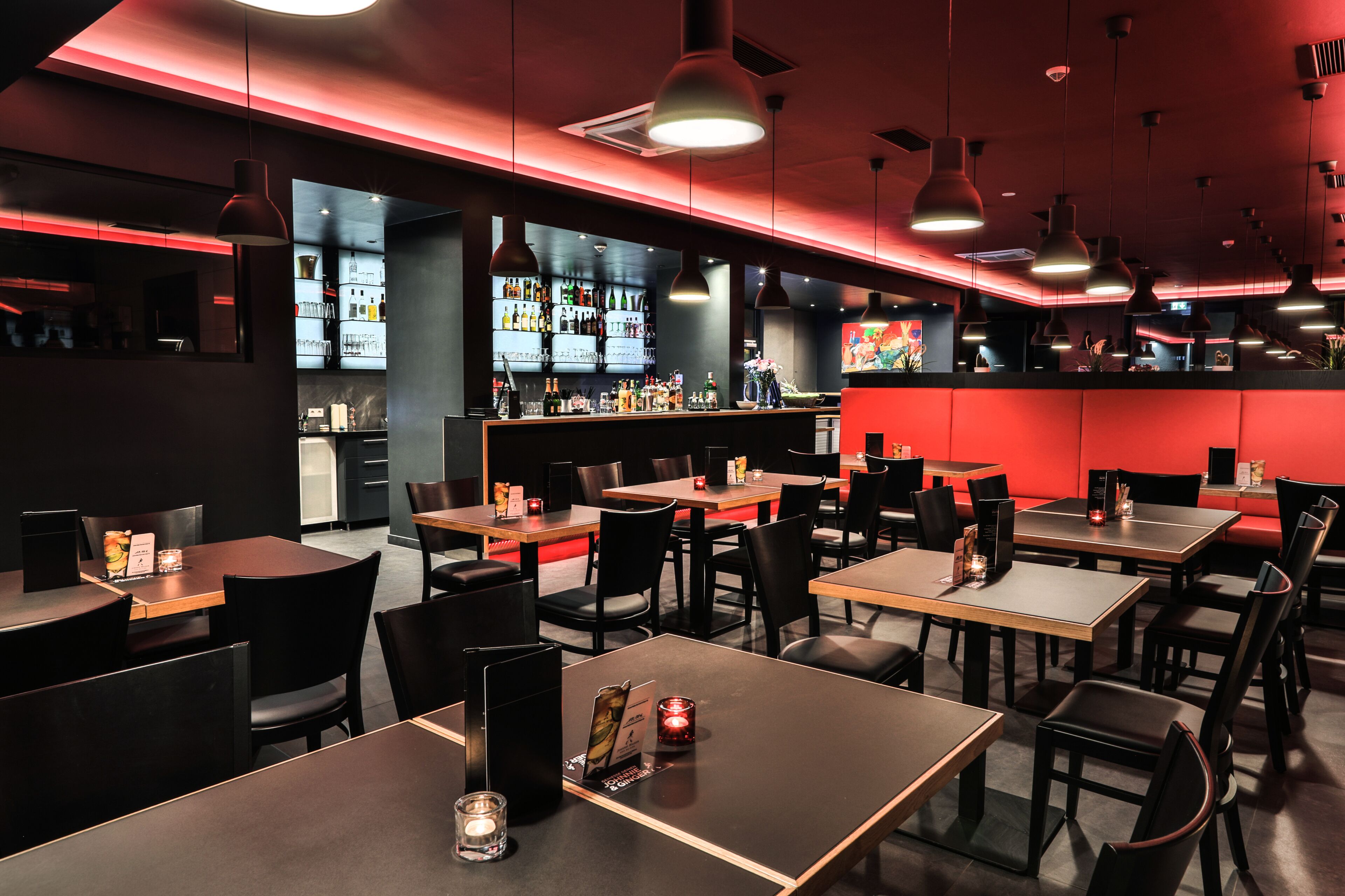 A restaurant with multiple tables and chairs, a bar area, and a kitchen visible through the windows.
