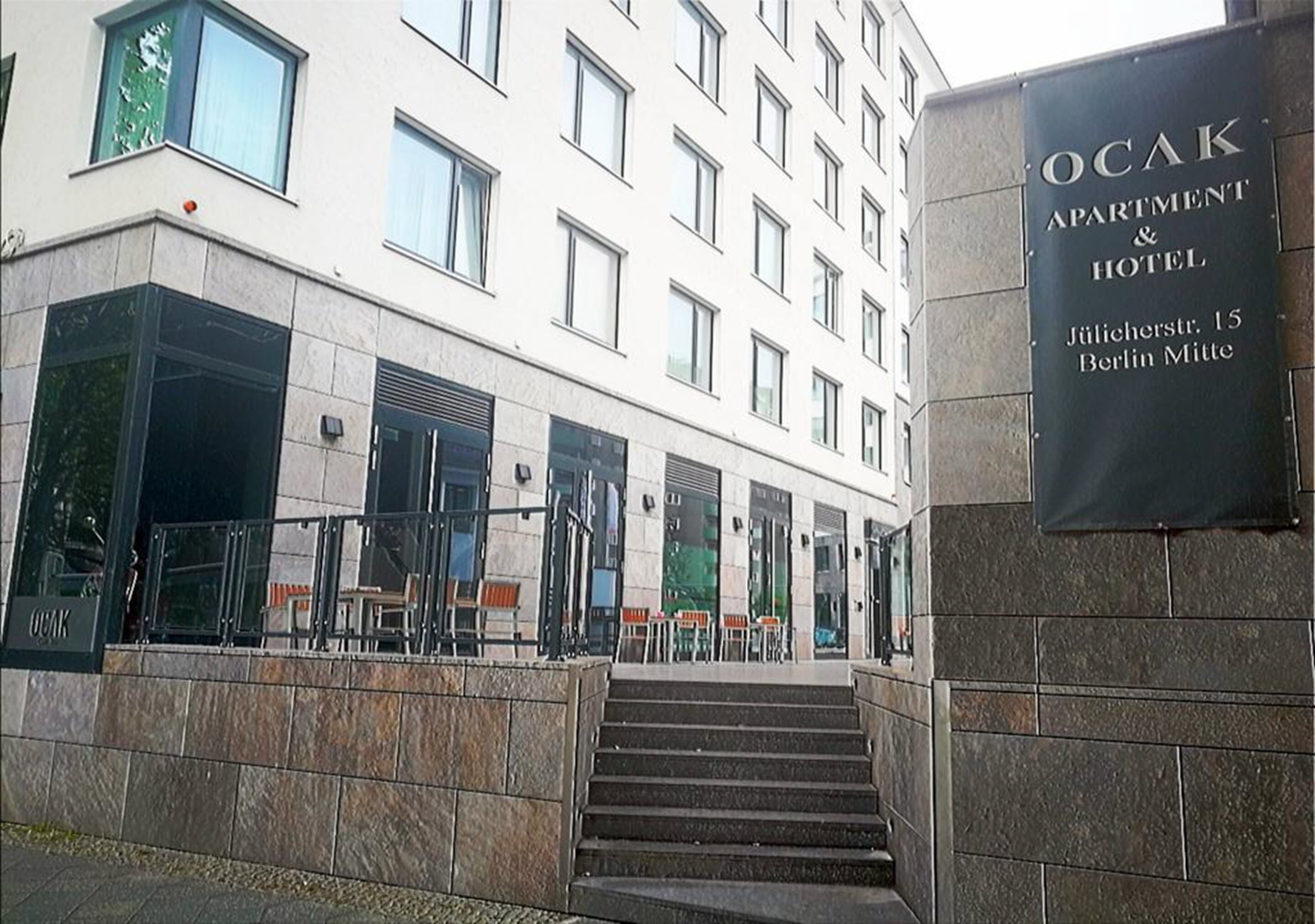 L’entrée d’un immeuble, avec une enseigne indiquant « OCAK APARTMENT & HOTEL » sur le côté droit.
