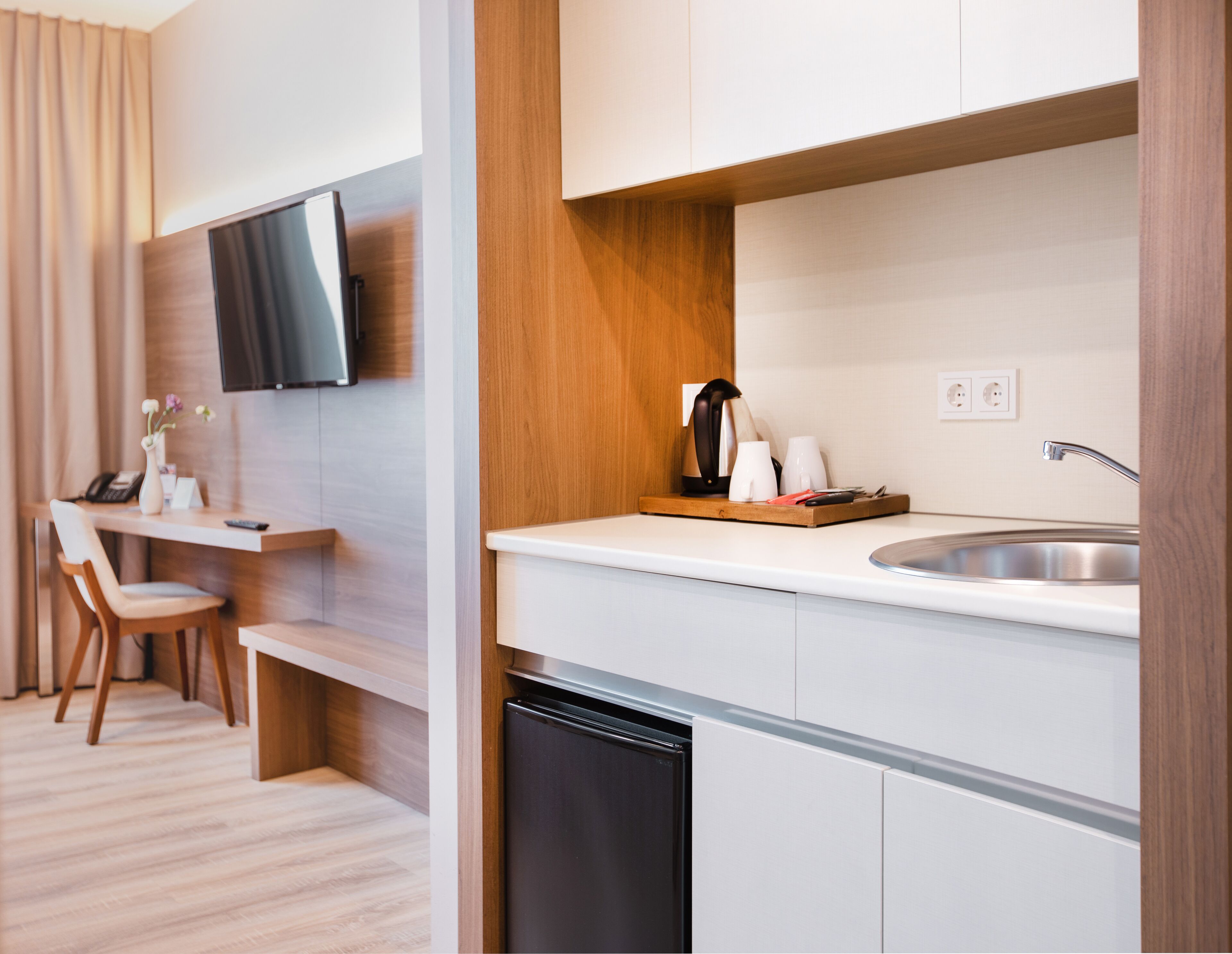 A modern kitchen with a built-in dishwasher, a wooden countertop, a sink, and a flat-screen TV mounted on the wall.