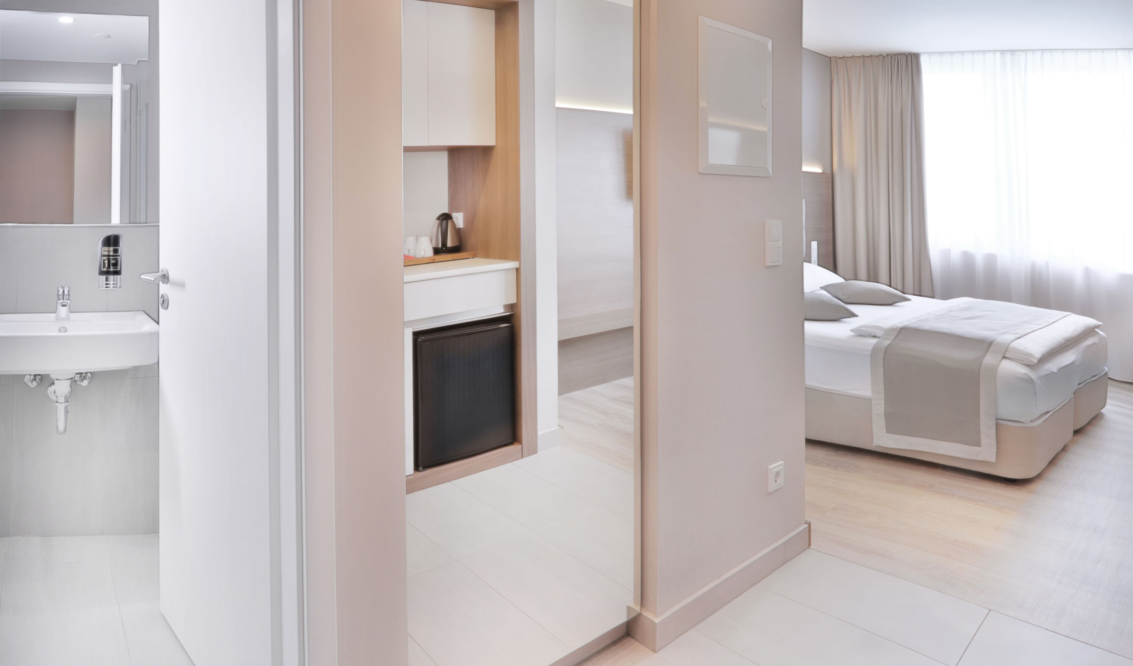 A modern hotel room with a bathroom, kitchenette, and a bed.