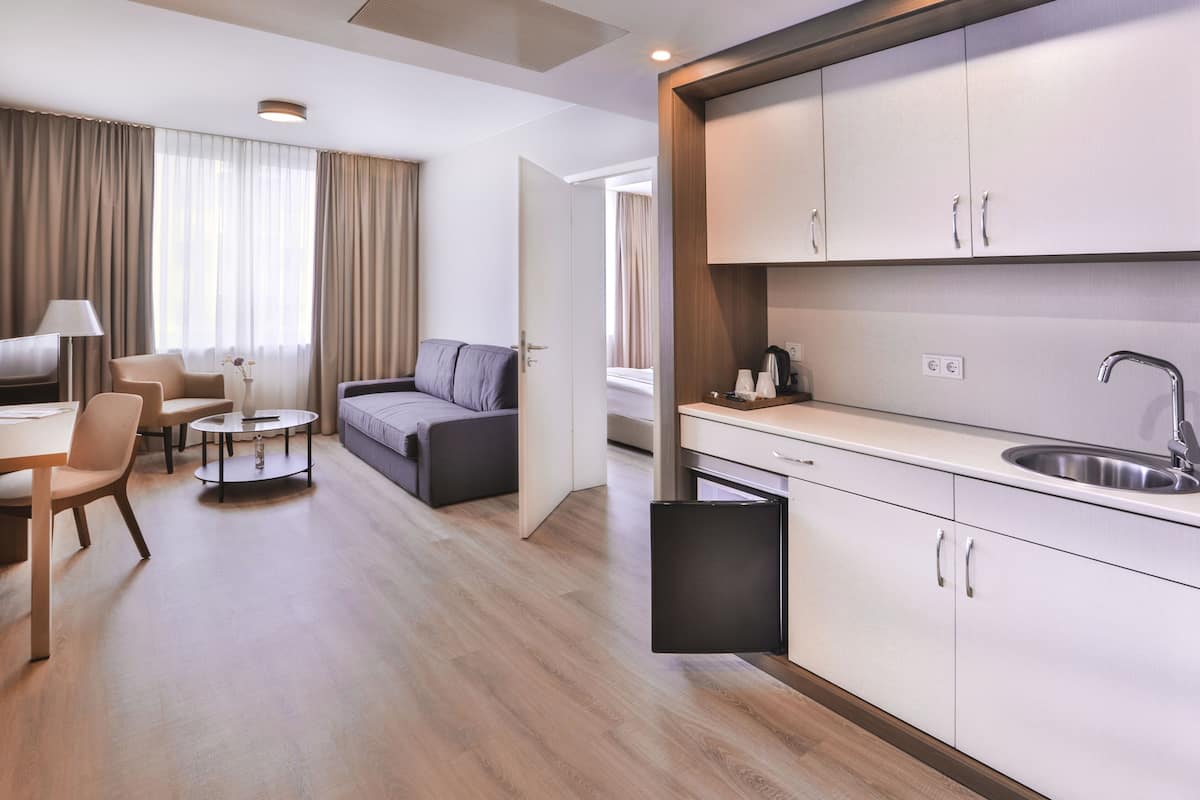Une chambre d’hôtel moderne équipée d’une kitchenette, d’un canapé, d’une table à manger et d’un téléviseur.