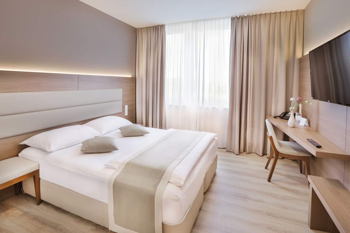 Une chambre d’hôtel moderne avec un grand lit, un bureau et une télévision.