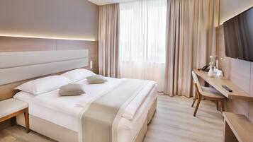 Une chambre d’hôtel moderne avec un grand lit, un bureau et une télévision.