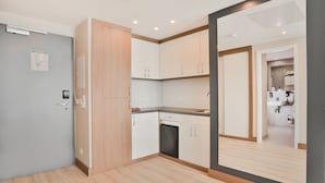 Een moderne keuken met lichte houten kastjes, een ingebouwde oven en een aanrecht.