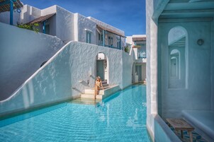 Una piscina al aire libre, sombrillas, sillones reclinables de piscina