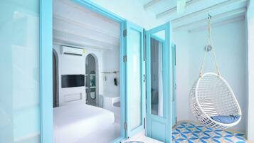 A room with a bed, a hanging chair, and a bathtub.
